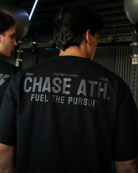  Oversized zwart T-shirt van Chase Athletics – model Fuel The Pursuit Tee, ontworpen voor comfort en stijl tijdens het sporten of in je vrije tijd.